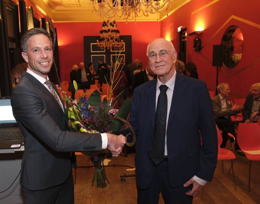 Bloemen voor scheidend voorzitter Herman Koeter uit handen van algemeen secretaris Ferry Braunstahl